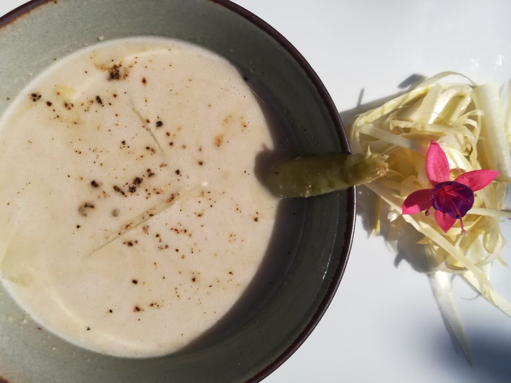 bol con sopa fría adornada con pimienta negra y un trozo de espárrago