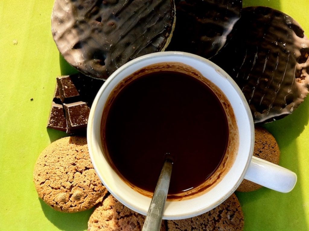 una taza de chocolate junto a galletas de chocolate, onzas de chocolate y galletas de avena