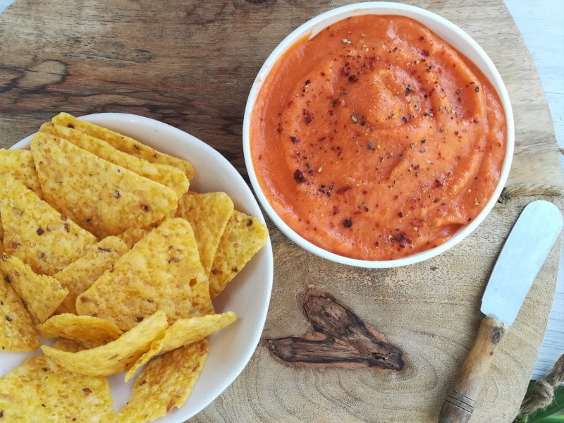 un plato de nachos junto a un cuenco con pure de patata y pimento condimentado con pimienta negra y roja