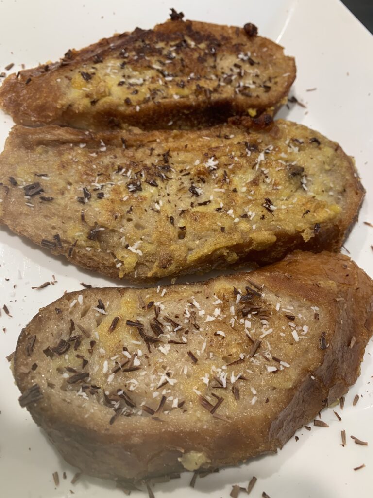 tres torrijas veganas sobre una bandeja blanca llevan espolvoreado chocolate y coco