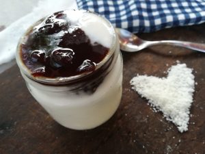 yogur vegano con leche de coco en un tarro y topping de mermelada de ciruelas